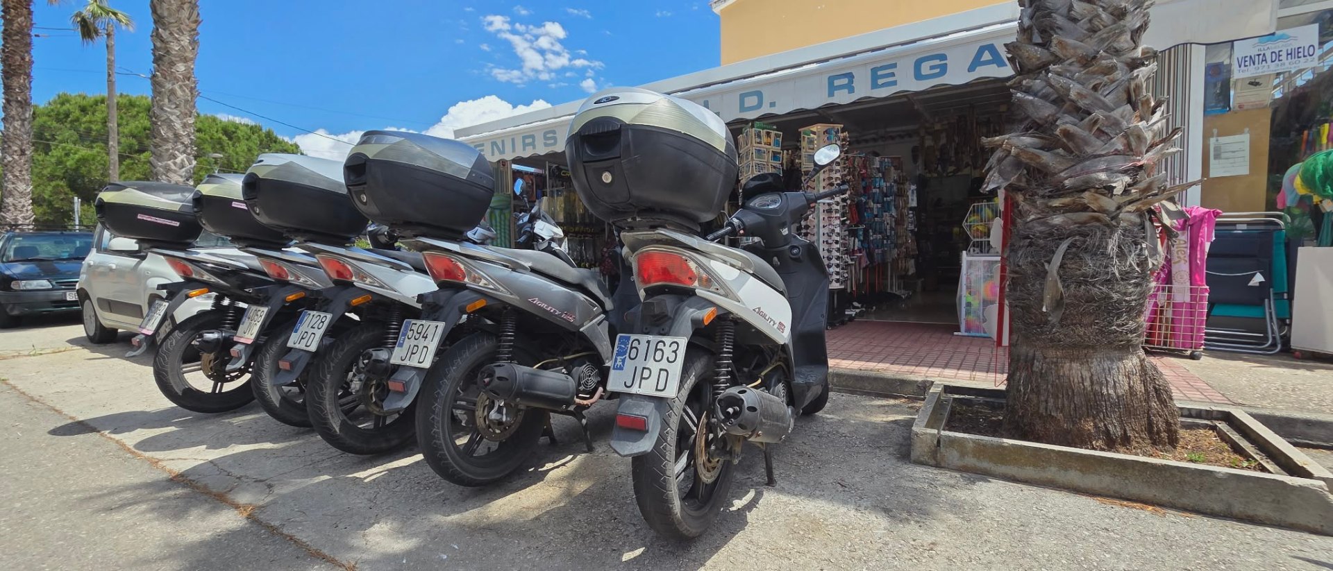 Cuatro motos 125cc Kymco Agility aparcadas frente a la tienda